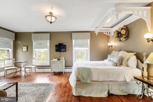 bedroom with multiple windows and dark wood-type flooring