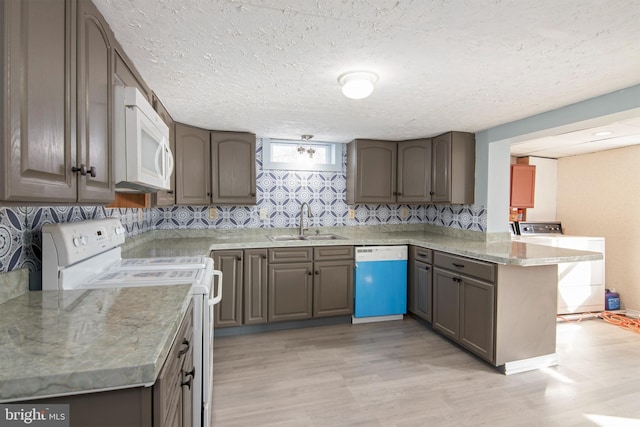 kitchen with washer / dryer, sink, light wood-type flooring, kitchen peninsula, and white appliances