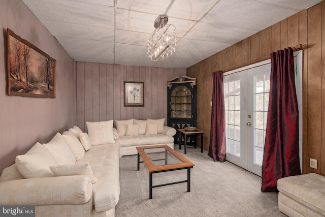 carpeted living room featuring french doors and wood walls