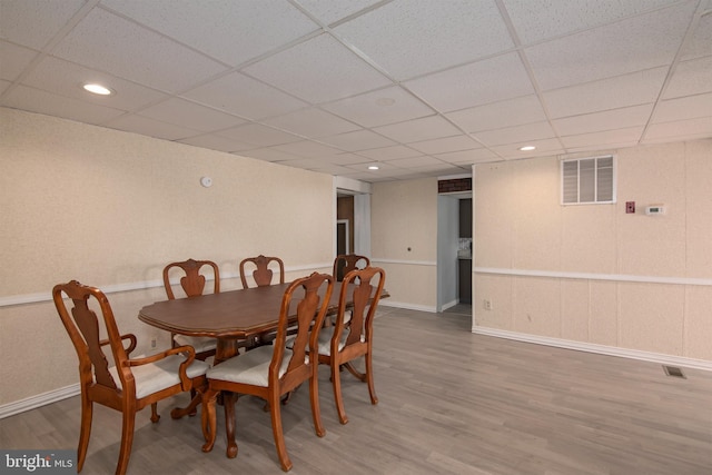 dining area with hardwood / wood-style flooring and a paneled ceiling