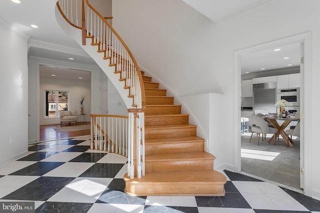 staircase with a towering ceiling and ornamental molding