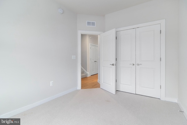 unfurnished bedroom with light carpet and a closet