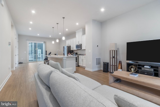 living room featuring sink and light hardwood / wood-style flooring