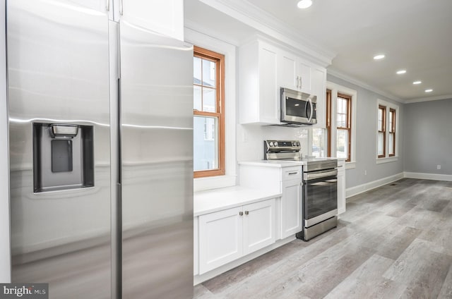 kitchen with white cabinetry, ornamental molding, stainless steel appliances, and light hardwood / wood-style floors