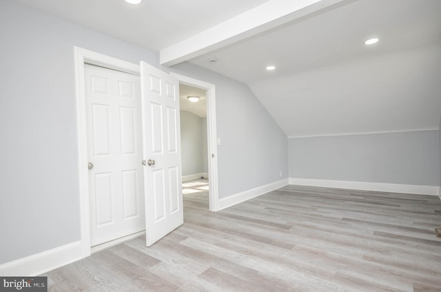 additional living space with light hardwood / wood-style flooring and vaulted ceiling with beams