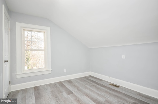 additional living space featuring light hardwood / wood-style flooring, a wealth of natural light, and vaulted ceiling