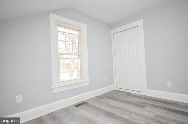 empty room with lofted ceiling and light hardwood / wood-style flooring