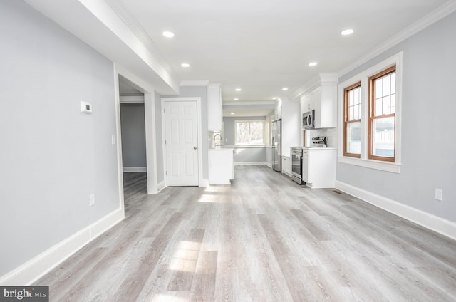 unfurnished living room with ornamental molding and light hardwood / wood-style floors