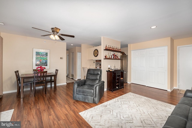 living room featuring ceiling fan, indoor bar, and dark hardwood / wood-style flooring