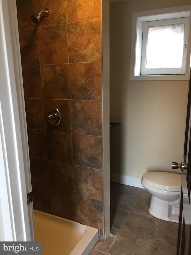 bathroom featuring toilet and a tile shower