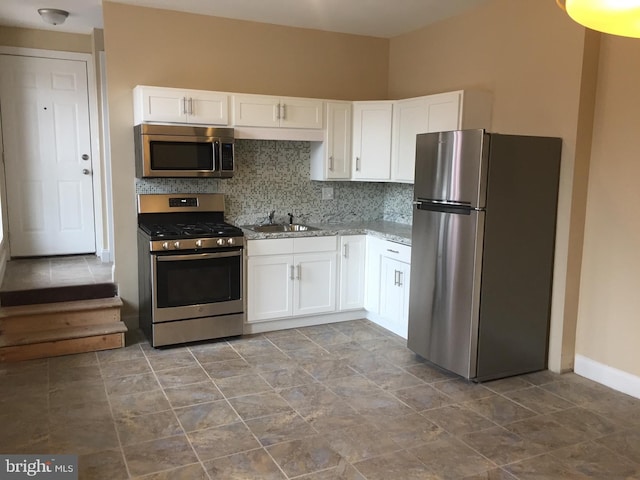 kitchen with sink, tasteful backsplash, light stone counters, stainless steel appliances, and white cabinets