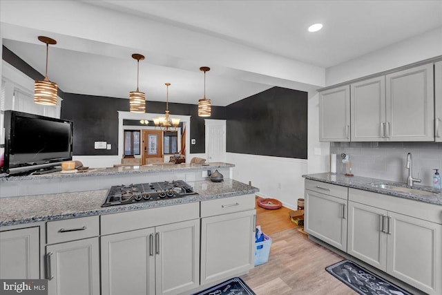 kitchen with stainless steel gas stovetop, sink, pendant lighting, and light wood-type flooring