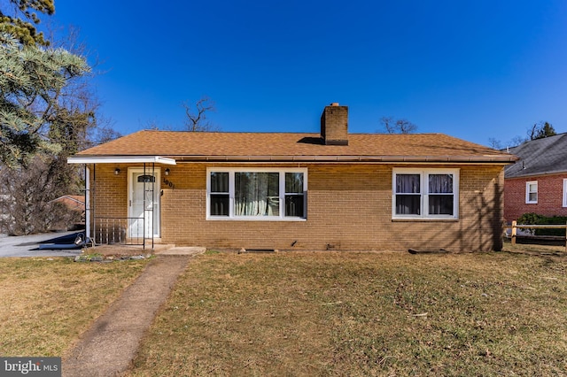 view of front of home with brick siding, a chimney, and a front yard