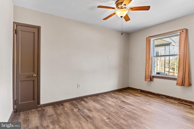 spare room with baseboards, wood finished floors, and a ceiling fan