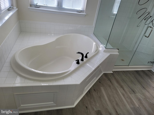 bathroom with plenty of natural light, shower with separate bathtub, and wood-type flooring