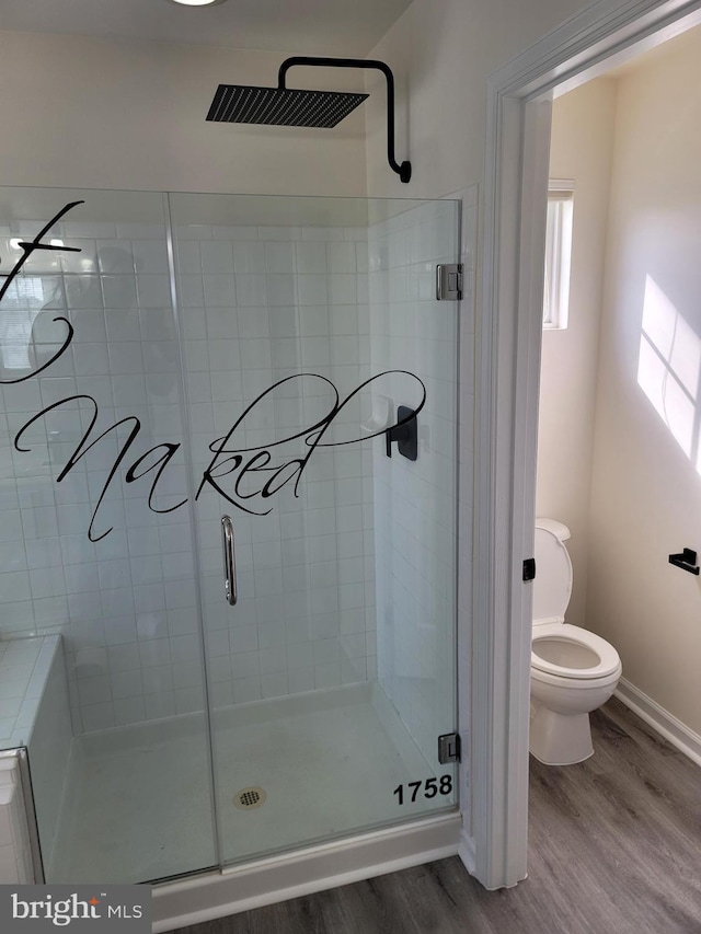 bathroom with walk in shower, toilet, and hardwood / wood-style floors