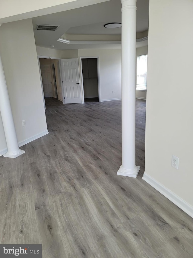 unfurnished room with hardwood / wood-style flooring, a raised ceiling, and ornate columns