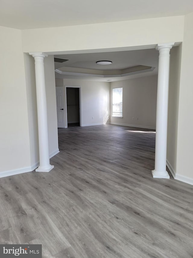 spare room featuring decorative columns and hardwood / wood-style floors