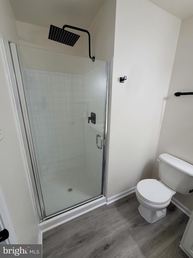 bathroom featuring hardwood / wood-style flooring, toilet, and a shower with shower door