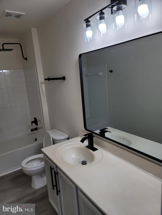 full bathroom with vanity, tiled shower / bath, wood-type flooring, and toilet