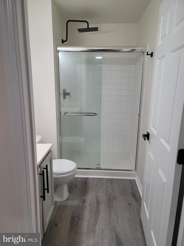 bathroom with an enclosed shower, hardwood / wood-style floors, vanity, and toilet