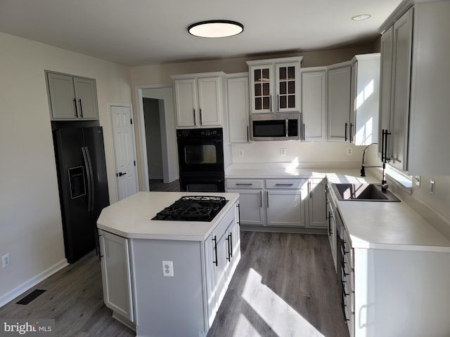 kitchen with sink, black appliances, light hardwood / wood-style flooring, a kitchen island, and white cabinets