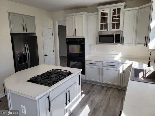 kitchen featuring a kitchen island, black appliances, white cabinets, and light wood-type flooring