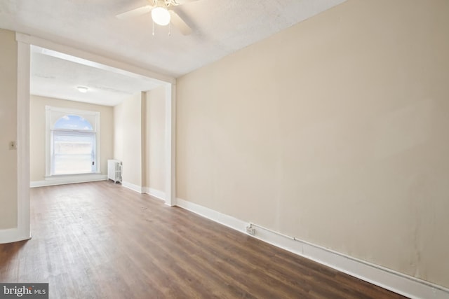 spare room featuring dark hardwood / wood-style floors, radiator heating unit, and ceiling fan