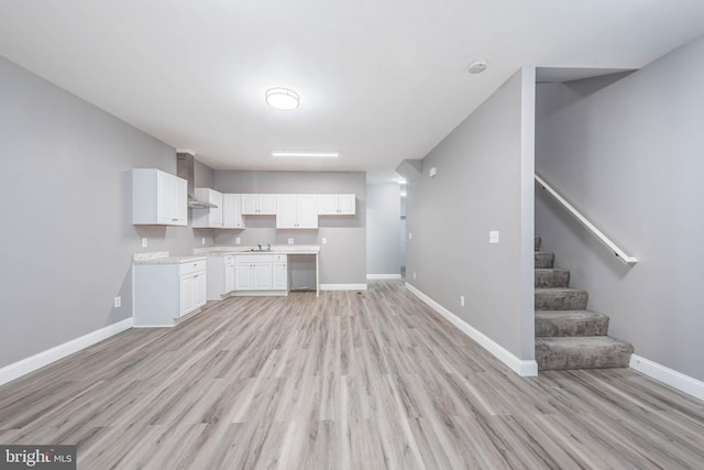 kitchen featuring light hardwood / wood-style flooring, white cabinets, and wall chimney exhaust hood