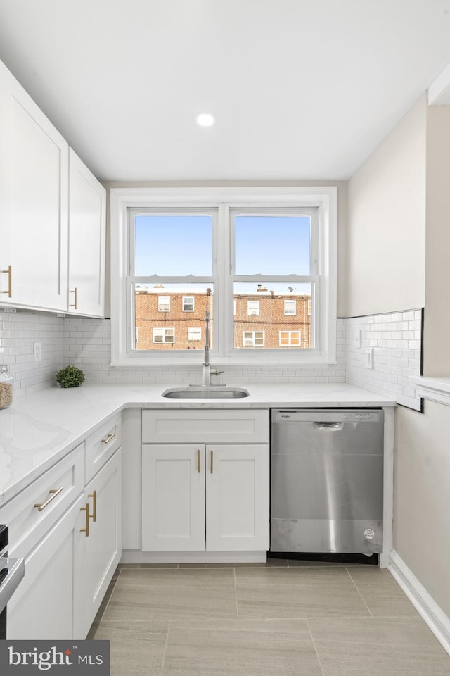 kitchen featuring a wealth of natural light, sink, stainless steel dishwasher, and white cabinets