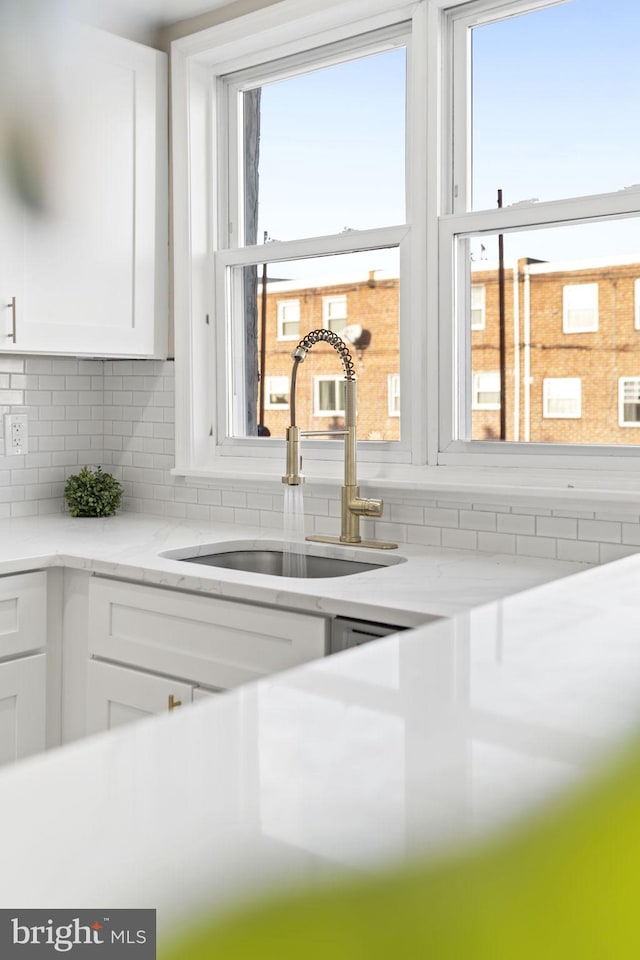 details with white cabinetry, sink, and backsplash