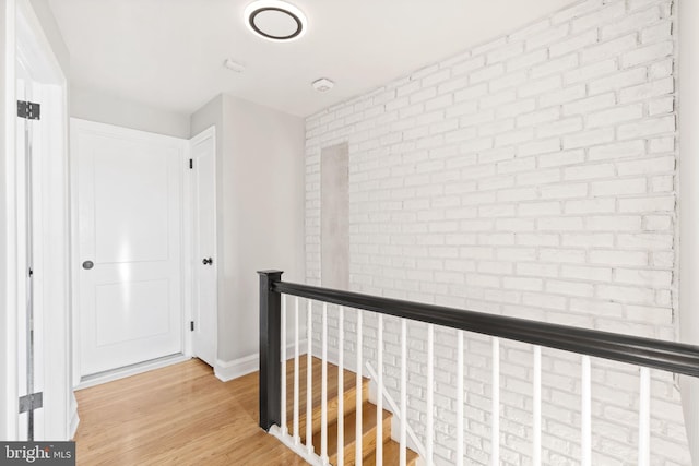 hallway with brick wall and light wood-type flooring