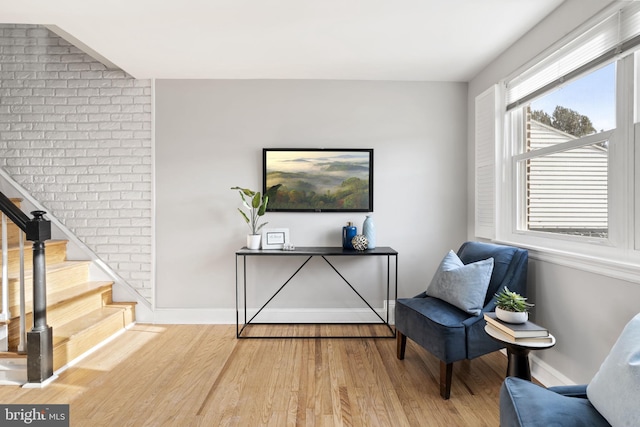 sitting room featuring wood-type flooring and brick wall