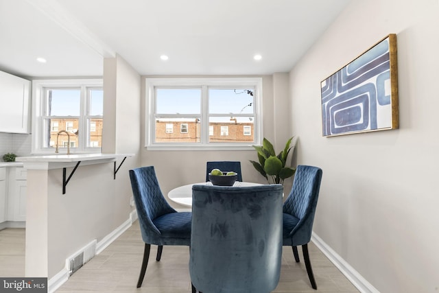 dining space with light wood-type flooring, sink, and a wealth of natural light