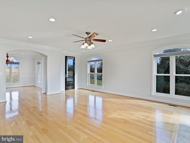 spare room with crown molding, ceiling fan with notable chandelier, and light wood-type flooring