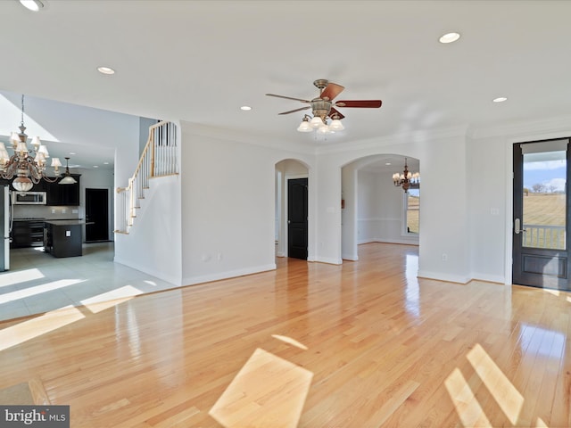 spare room with crown molding, ceiling fan with notable chandelier, and light wood-type flooring