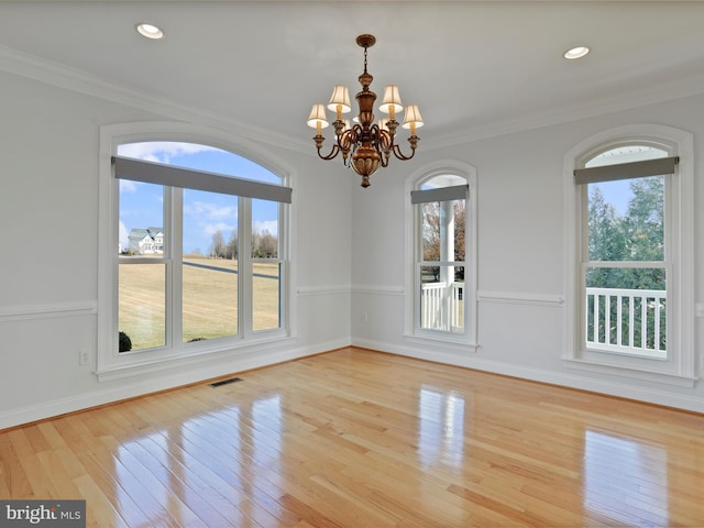 unfurnished dining area with crown molding, a notable chandelier, and light wood-type flooring