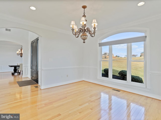 empty room with hardwood / wood-style flooring, ornamental molding, and a notable chandelier