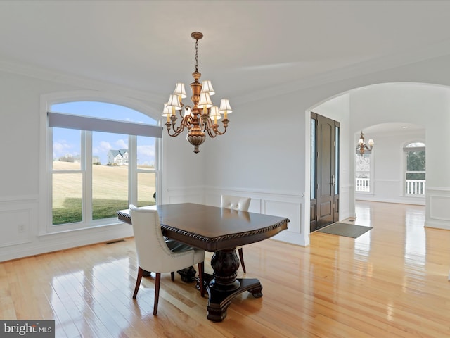 dining space featuring an inviting chandelier, ornamental molding, and light wood-type flooring