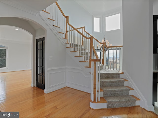 stairs with ornamental molding, plenty of natural light, and hardwood / wood-style floors