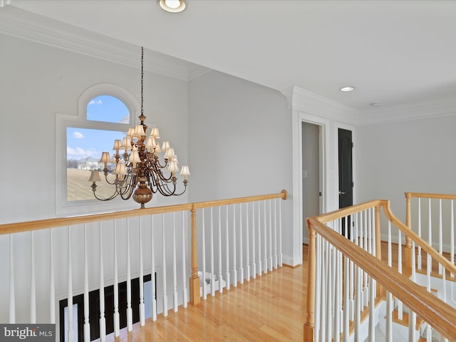 hall with hardwood / wood-style floors, crown molding, and a chandelier