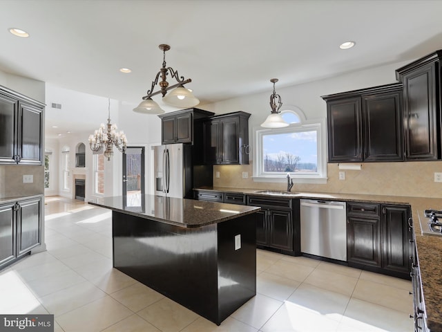 kitchen featuring a kitchen island, appliances with stainless steel finishes, decorative backsplash, and decorative light fixtures