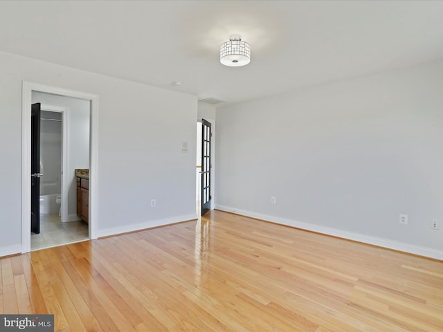 unfurnished bedroom featuring ensuite bath and light hardwood / wood-style flooring