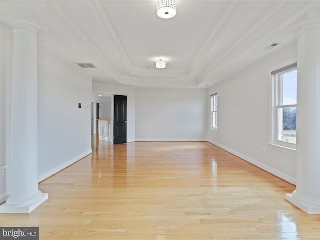 unfurnished room featuring ornate columns, crown molding, light hardwood / wood-style flooring, and a tray ceiling