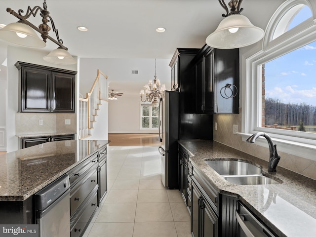 kitchen with appliances with stainless steel finishes, tasteful backsplash, sink, dark stone counters, and hanging light fixtures