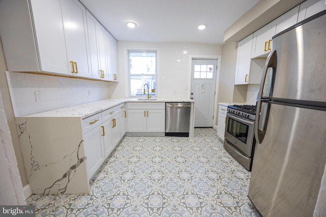 kitchen featuring sink, appliances with stainless steel finishes, light stone countertops, white cabinets, and decorative backsplash