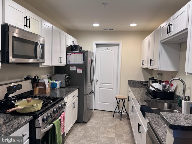 kitchen with white cabinetry, sink, dark stone counters, and appliances with stainless steel finishes