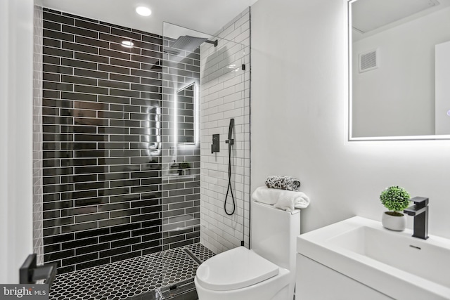 bathroom with vanity, tiled shower, and toilet