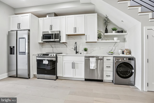 kitchen featuring stainless steel appliances, white cabinetry, sink, and washer / clothes dryer