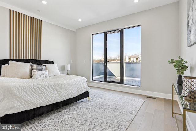 bedroom with a water view, hardwood / wood-style floors, and access to outside